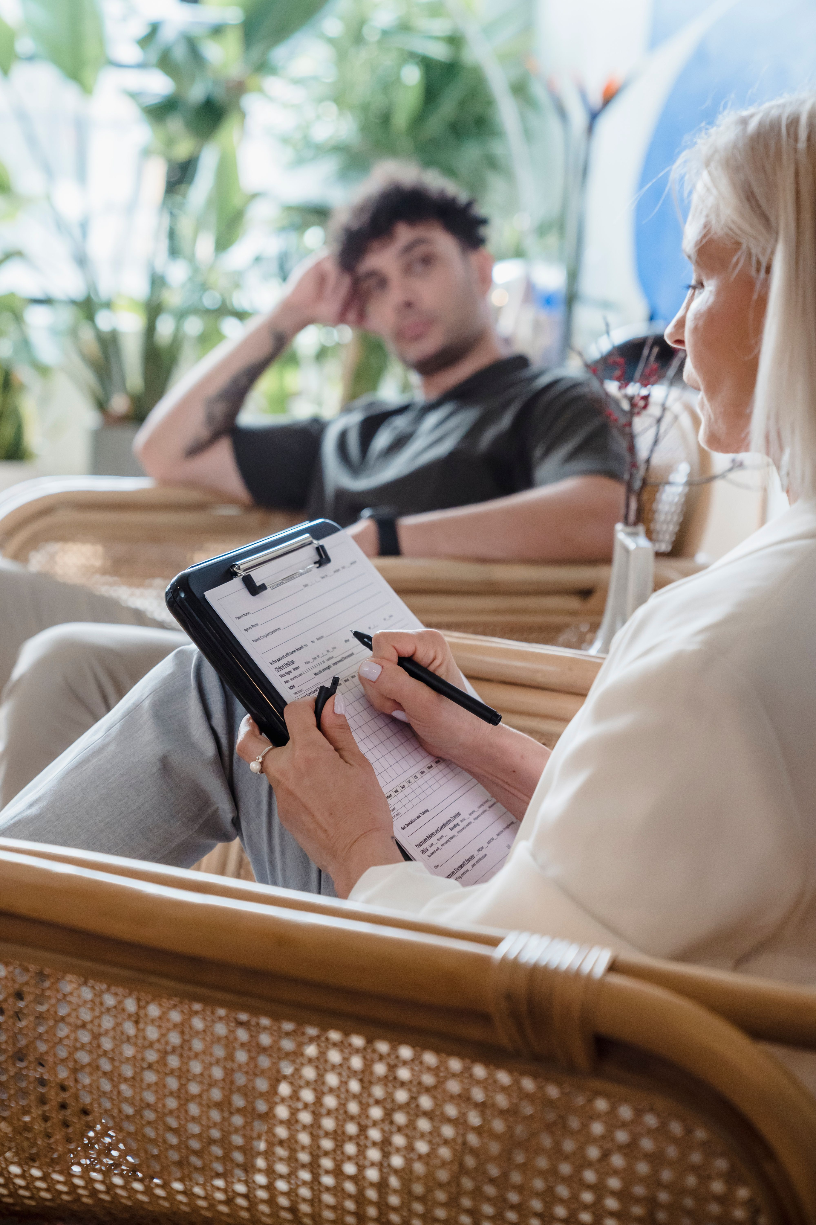 A clinician taking notes while a patient sits nearby