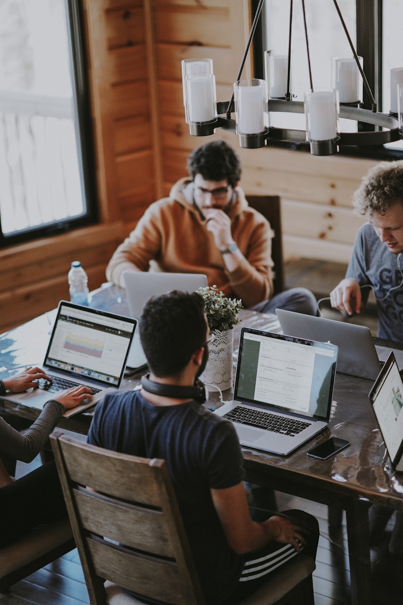 A small team collaborating around a table with laptops
